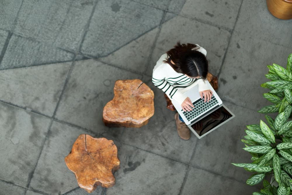 woman-typing-laptop-tree-trunk-bench.jpg